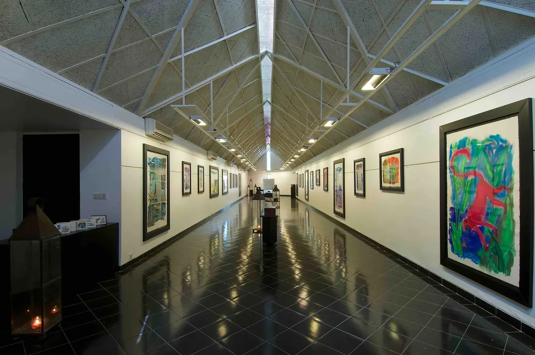 A long gallery hung with Hiren Patel's paintings, a reading table down the middle.