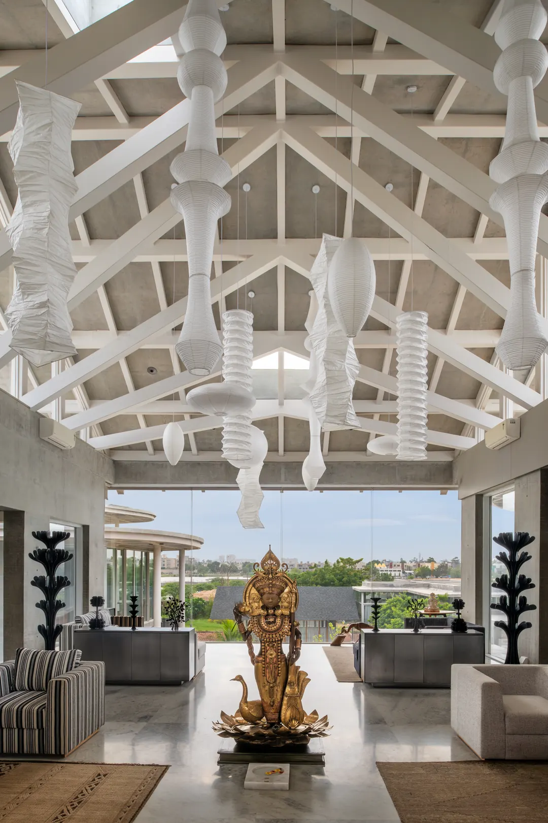 Sculptures in the double-height hall at Oxygen, under white trusses.