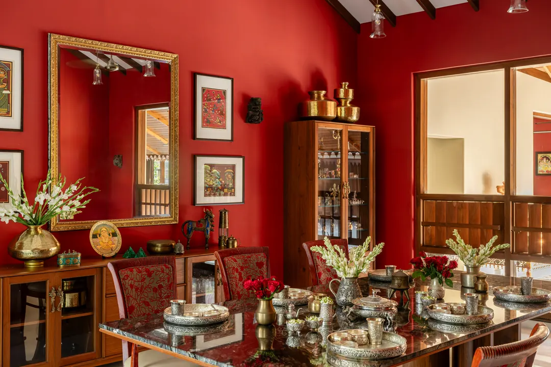 A red dining room styled with brass, white tuberoses and a set table.