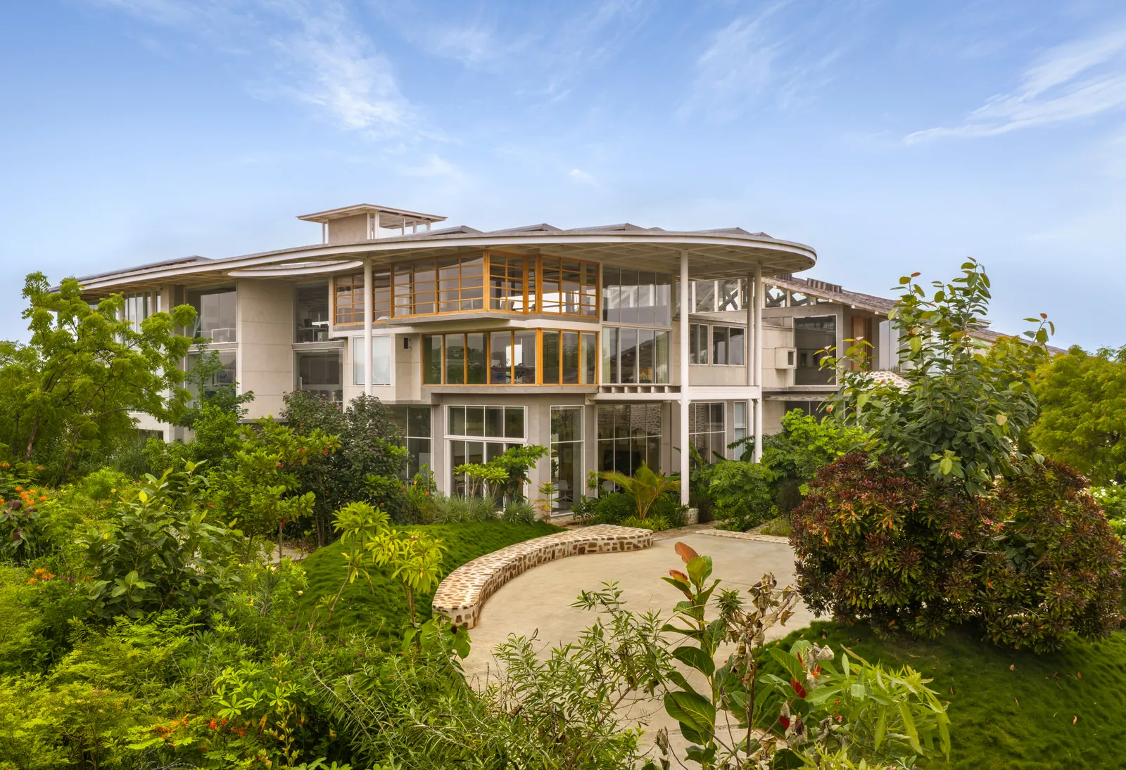 Oxygen, the studio: a curved roof over glass and white walls, rising out of a planted garden.