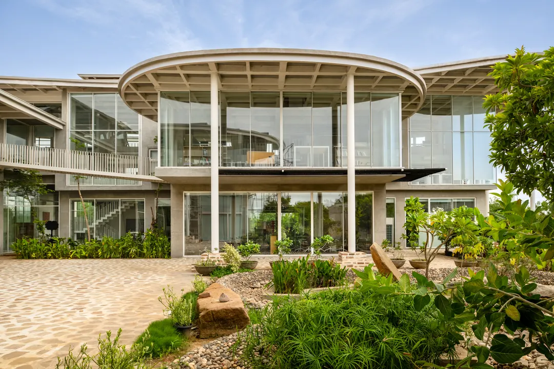 The studio building in daylight, glass walls under a curved coffered roof.
