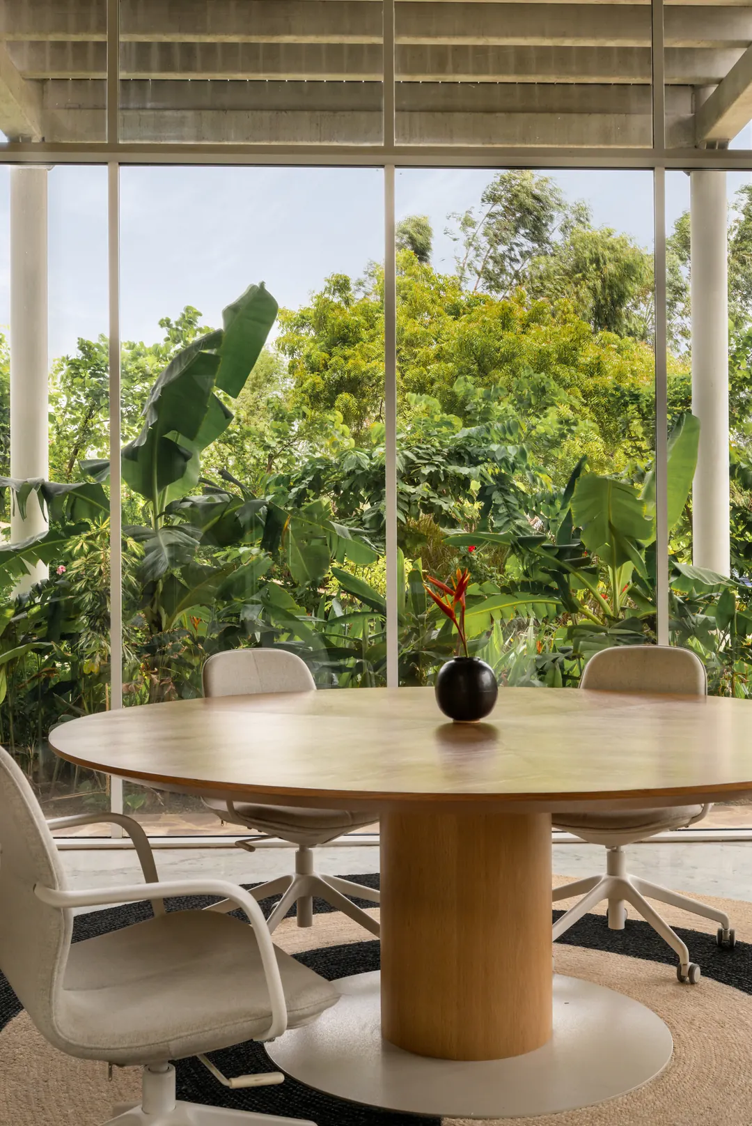 A meeting table by the glass, the garden beyond.