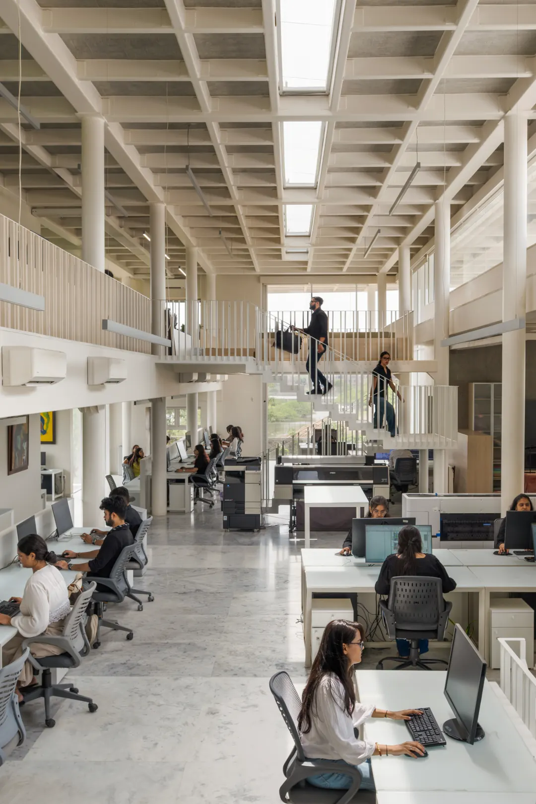 The long studio floor under a coffered roof, people at work.