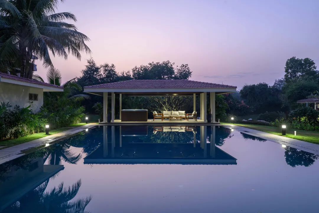 A pavilion across a still pool at dusk.
