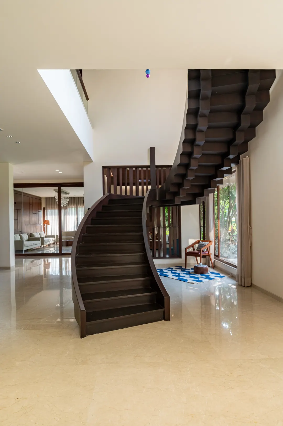 A black stair curving up through a white hall.