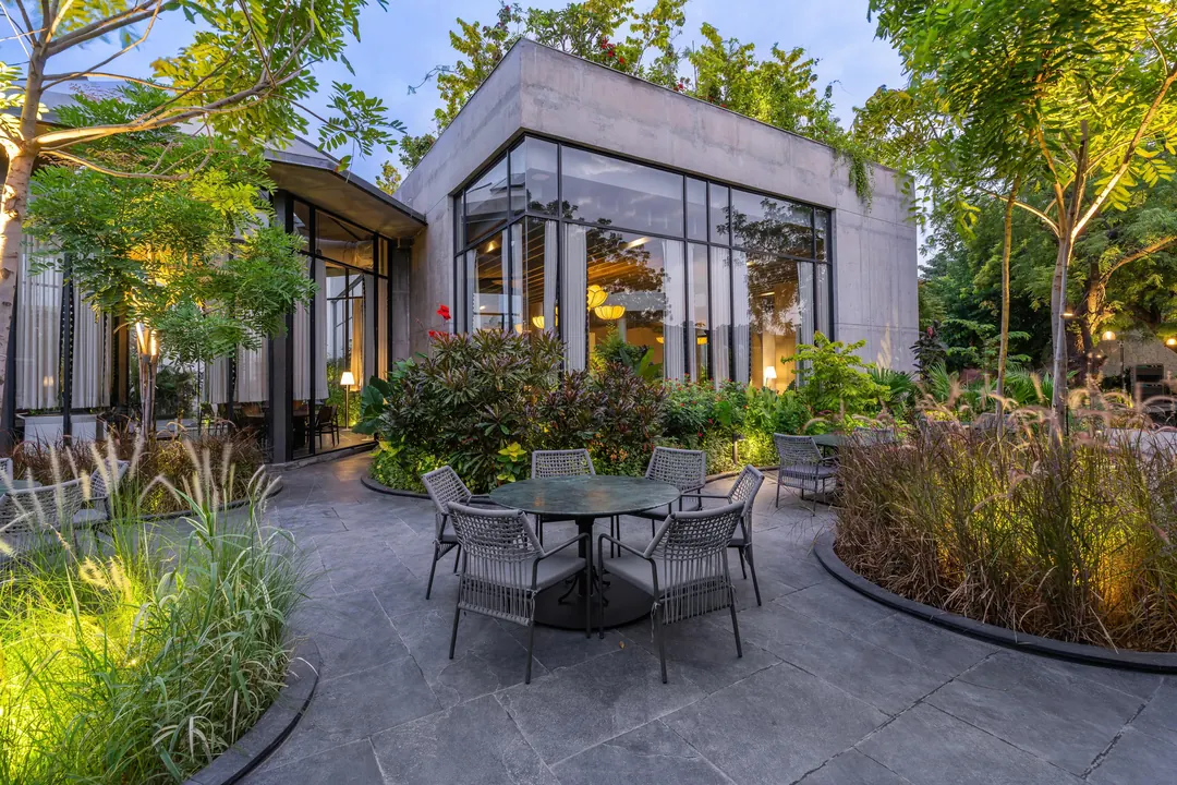 Tables in a planted court beside a glass pavilion.