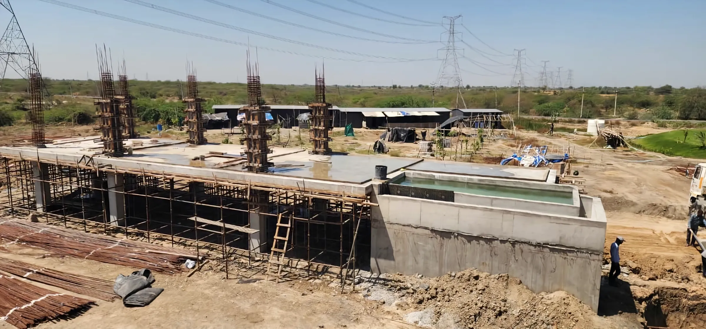 The concrete frame of a house going up, with a water tank cast beside it.