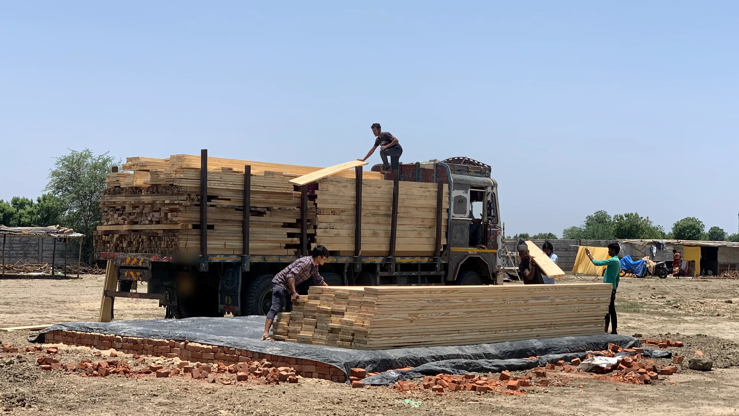 Timber arriving on site, unloaded and stacked by hand.