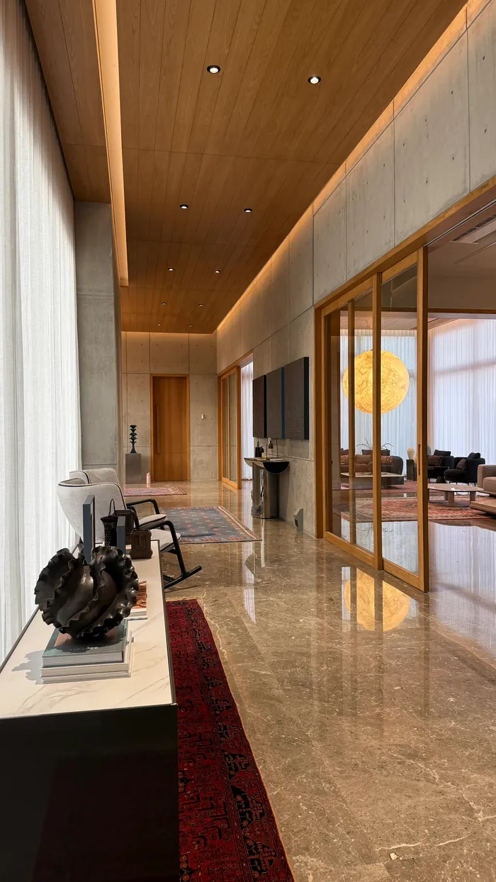 A long view through the house: stone, timber, glass and a moon of light.
