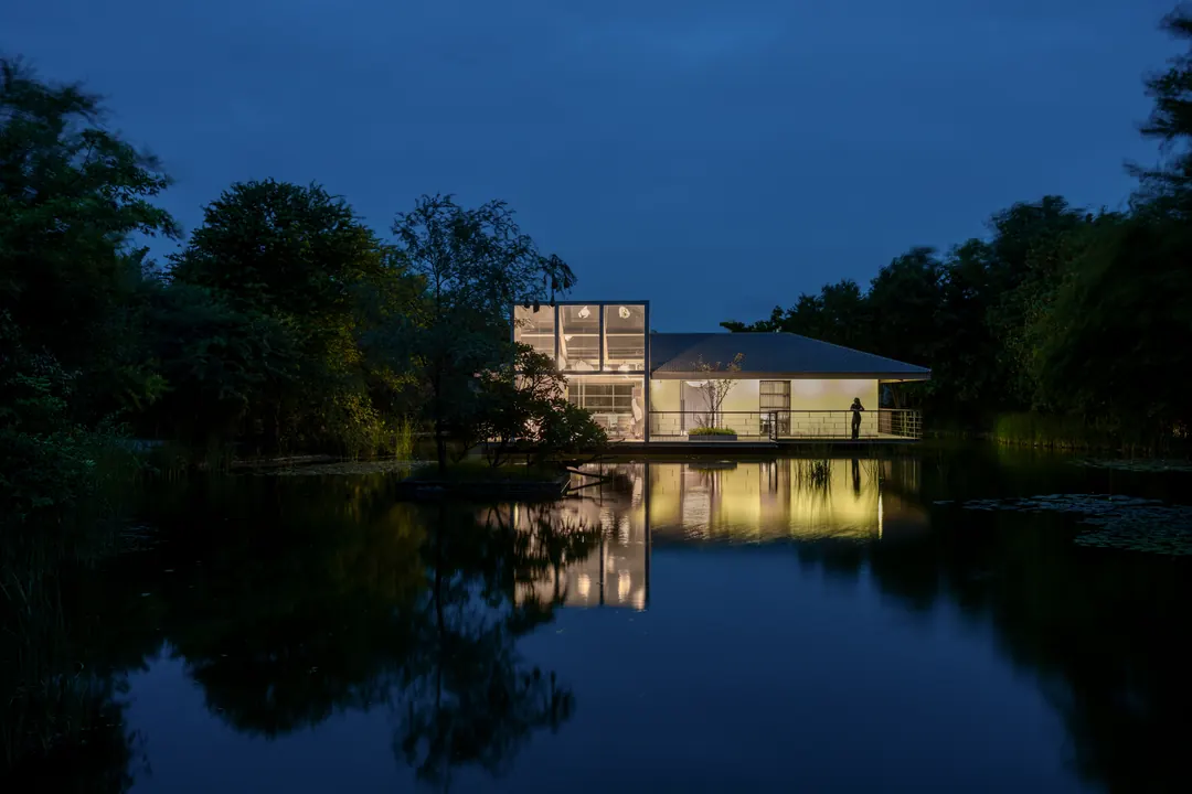 The glass house at Monkey Forest lit at dusk, reflected in the lake.