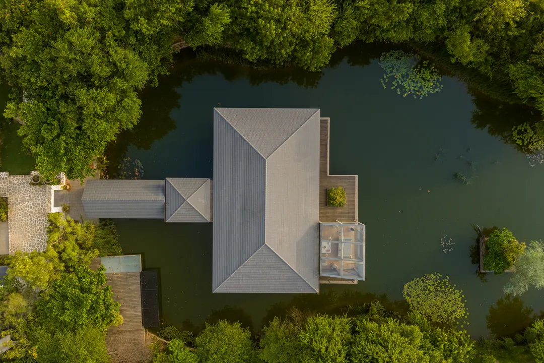 The glass house on the lake at Monkey Forest from the air, forest all around.